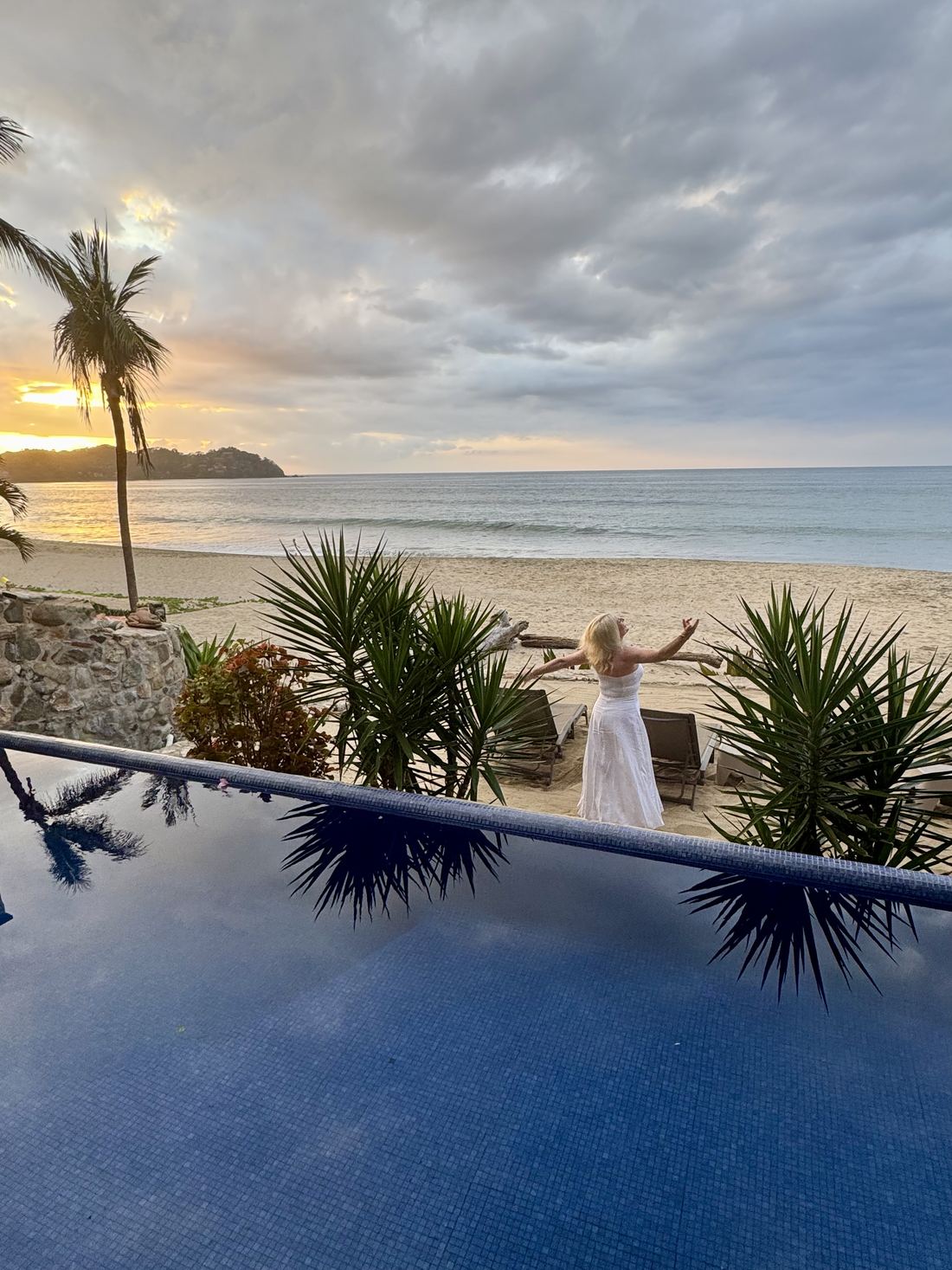 A woman with her arms open at sunset
