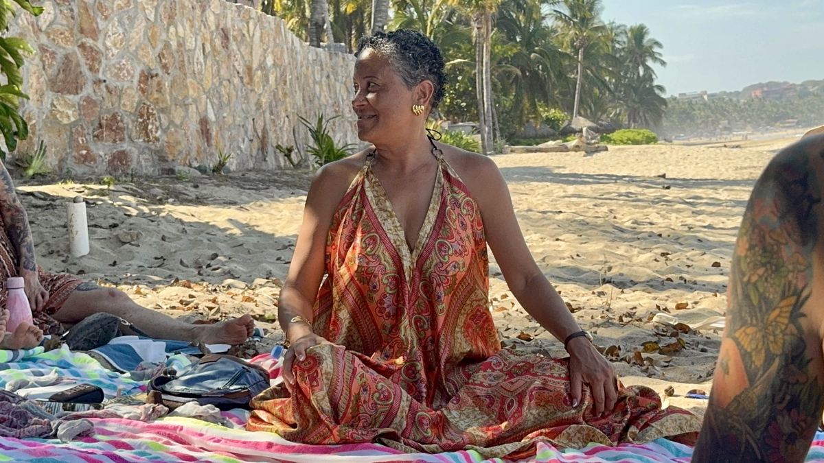 A woman seated on the beach at golden hour