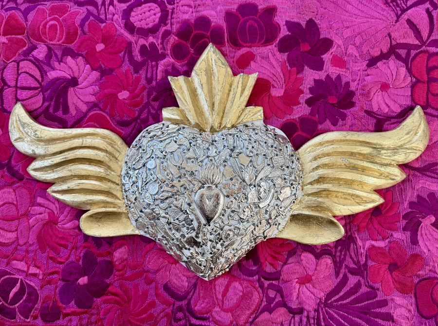 A milagro heart on embroidered cloth